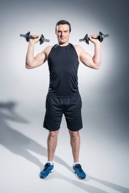 Çekici bir adam atlet gri arka plan üzerinde halter kaldırma