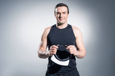 Gülümseyen adam VR gözlük gri arka plan üzerinde tutan