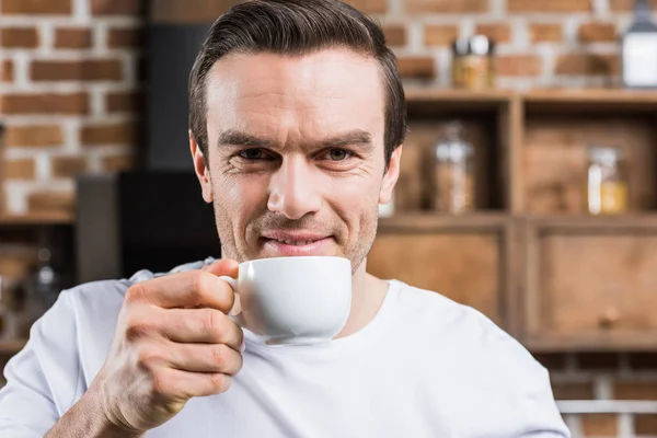 Stilig Man Dricka Kaffe Och Ler Mot Kameran Hemma — Stockfoto