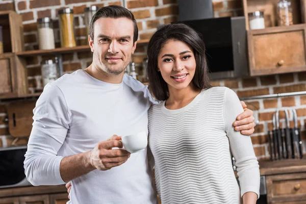 Multiethnic Couple Embracing Smiling Camera While Man Holding Cup Coffee — Stock Photo, Image