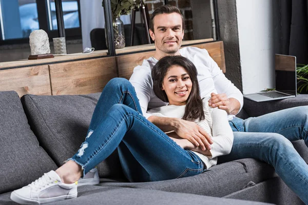 快乐的多民族情侣在沙发上微笑着在家休息 — 图库照片