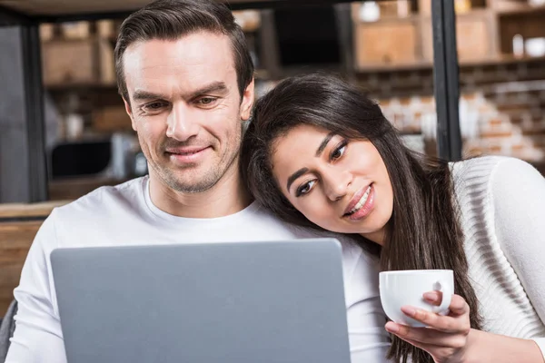 Sorrindo Casal Multiétnico Usando Laptop Juntos Enquanto Mulher Bebendo Chá — Fotos gratuitas