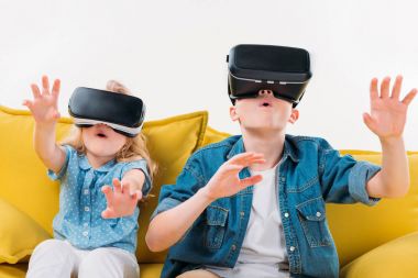 sanal gerçeklik kulaklık kullanarak ve sarı koltukta oturan heyecanlı kardeşler