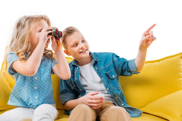 Boy Pointing While Sister Looking Binoculars Sitting Yellow Sofa — Stock Photo, Image