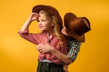 little cowboy embracing stylish cowgirl, isolated on yellow clipart