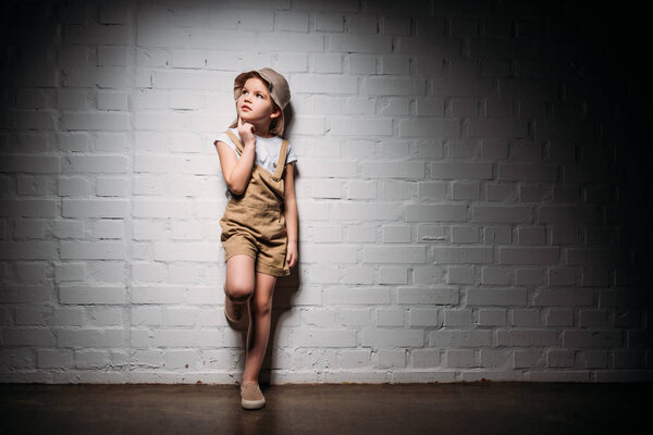 thoughtful female child in safari costume standing at white wall
