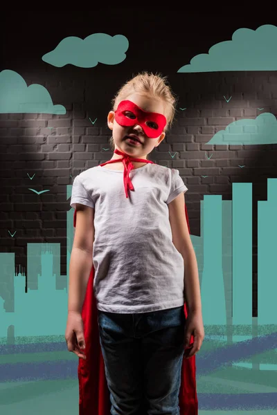 Ребенок Костюме Супергероя Красной Маске Плаще Городской Иллюстрацией Заднем Плане — Бесплатное стоковое фото