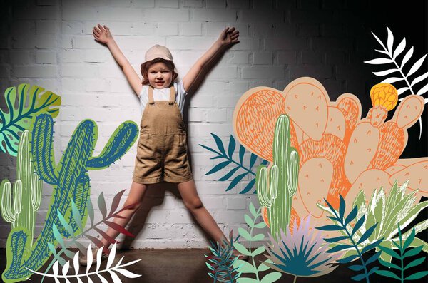 little child in safari costume standing at white wall with cactuses illustration
