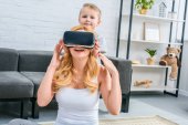 Mutter mit Virtual-Reality-Headset und kleiner Sohn im Hintergrund 