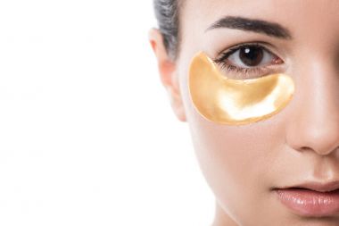 beyaz izole kamera bakarak göz bandı altında nemlendirici ile güzel kızın kırpılmış görüntü