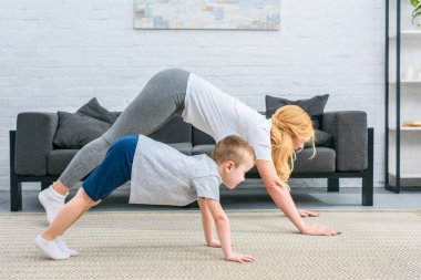 Anne ve oğlu adho mukha svanasana konumda yoga paspaslar üzerinde yan görünüm