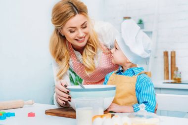 Anne ve oğlu birlikte kase ve malzemeler ile masada yemek gülümseyen 