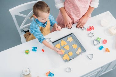 High angle view of mother and son putting dough for cookies on baking sheet  clipart
