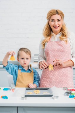 Happy mother and son holding figured dough for cookies  clipart
