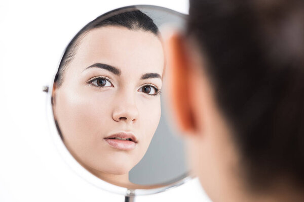 back view of beautiful girl looking at table mirror isolated on white