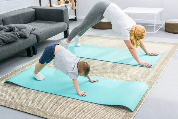 Mother and little boy in adho mukha svanasana position on yoga mats — Stock Image Mother Little Boy Adho Mukha Svanasana Position Yoga Mats Stock Image