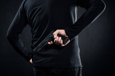 Rear view of gun in hands of gangster on black clipart