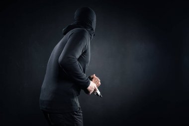 Robber with gun sneaking on black background clipart