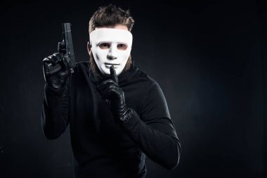Silah tutan ve sessizlik jest gösterilen maskeli hırsız