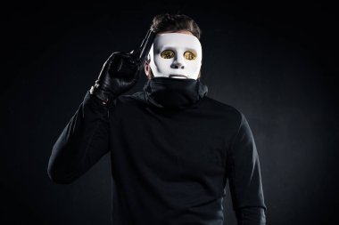 Thief in mask and bitcoins on eyes holding gun clipart