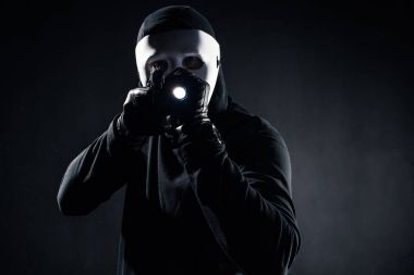 Burglar in mask and balaclava aiming with gun and flashlight clipart