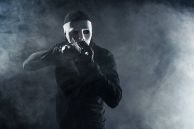 Man in mask and balaclava aiming with gun and flashlight clipart