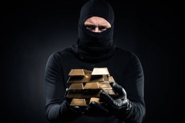 Man in balaclava holding gold bullions in his hands clipart