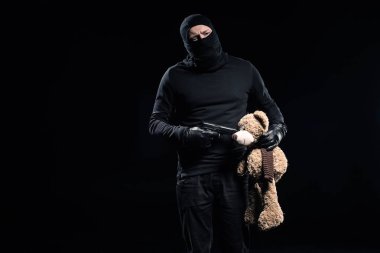Burglar in balaclava holding gun and teddy bear clipart