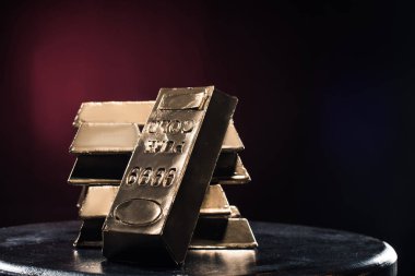 Stack of golden ingots on table against red background clipart