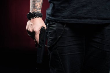 Close-up view of gun in male hand on red background