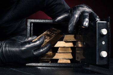 Cropped view of thief stealing gold ingots from safe clipart