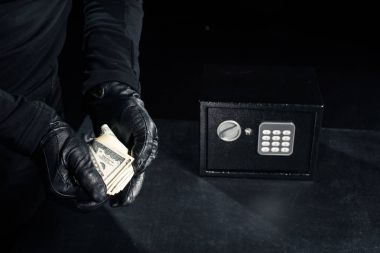 Close-up view of robber in gloves taking dollars from safe clipart