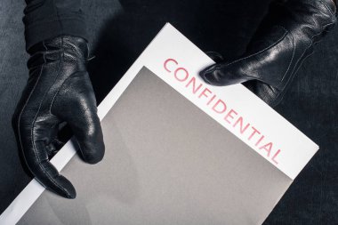 Close-up view of criminal holding folder with confidential documents clipart