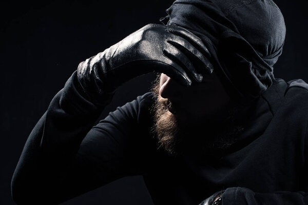  Robber in balaclava leaning his head on hand