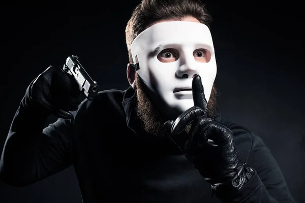 Robber Mask Holding Gun Showing Silence Gesture — Free Stock Photo