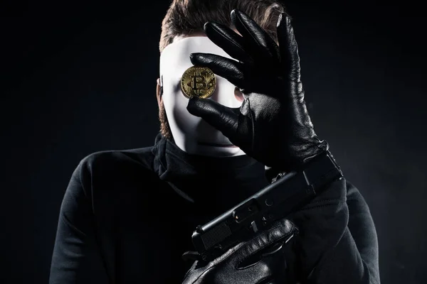 Dieb mit weißer Maske mit Pistole und goldenem Bitcoin — Stockbild Dieb Mit Weißer Maske Mit Pistole Und Goldenem Bitcoin — Stockfoto