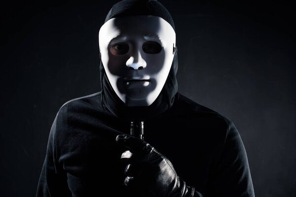 Robber in white mask holding flashlight
