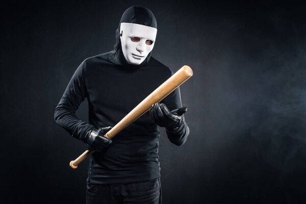 Criminal in mask and balaclava holding baseball bat