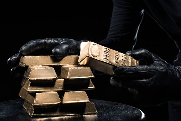 Close-up view of golden bars in hands of thief