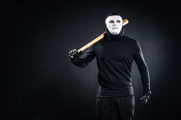 Burglar in mask and balaclava holding baseball bat