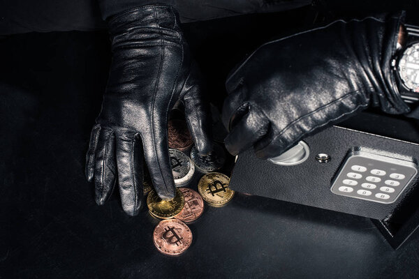 Cropped view of robber stealing bitcoin from safe