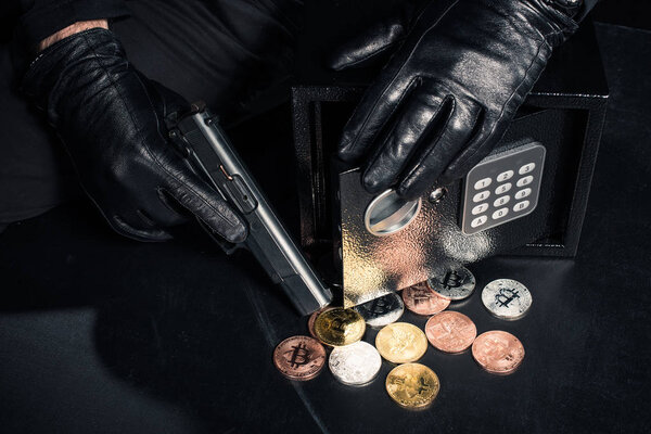 Close-up view of robber with gun stealing bitcoin from safe