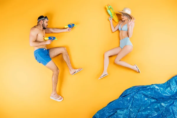 年轻夫妇在泳装玩水枪想象海滩 暑假概念 — 图库照片
