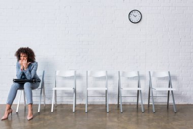 Nervous female candidate with briefcase waiting for interview clipart