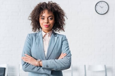 Attractive african american businesswoman standing with folded arms clipart