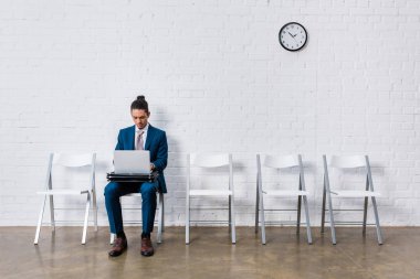 Businessman working on laptop while sitting on chair clipart