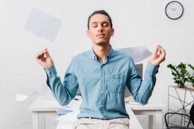 Rahatlatıcı ve Office belgeleri uçan ile meditasyon genç işadamı