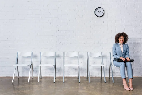 Wanita Tersenyum Dengan Koper Menunggu Wawancara Sambil Duduk Kursi — Stok Foto