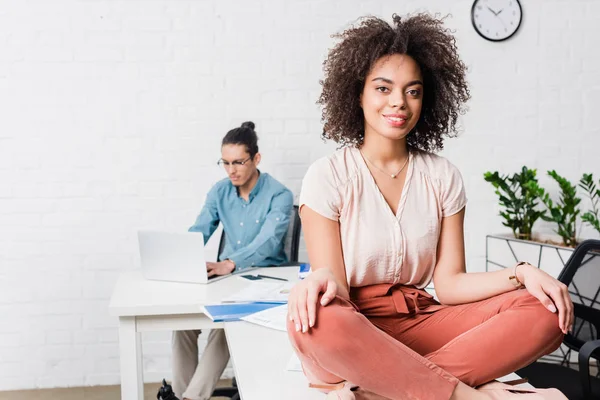 Geschäftsfrau Sitzt Lotusposition Büro Männlicher Kollege Arbeitet Laptop Dahinter — Stockfoto