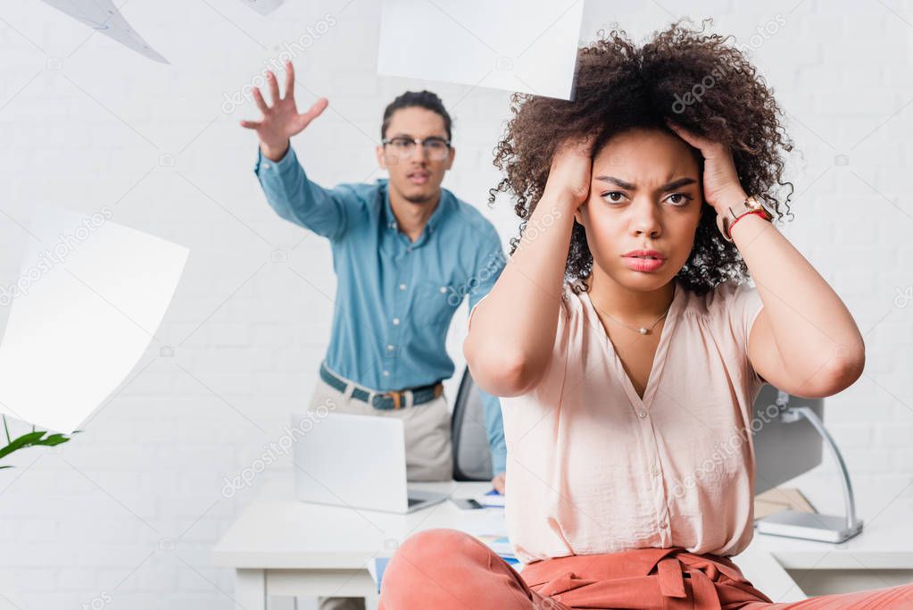 Businesswoman suffering from headache while her male colleague yelling in office